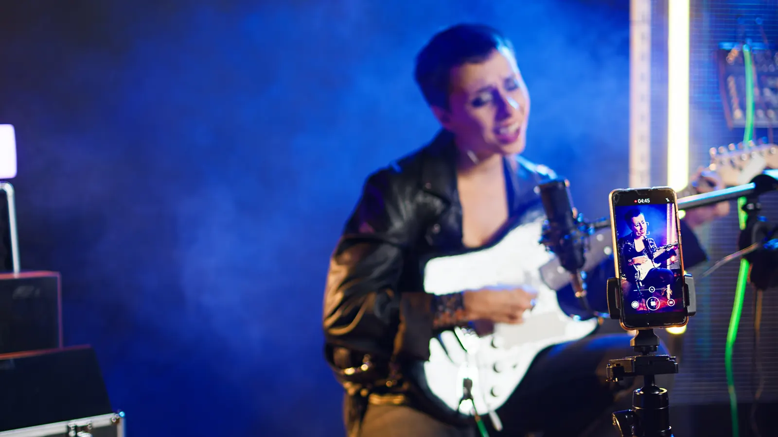 Musikerin streamt live mit Gitarre und Smartphone