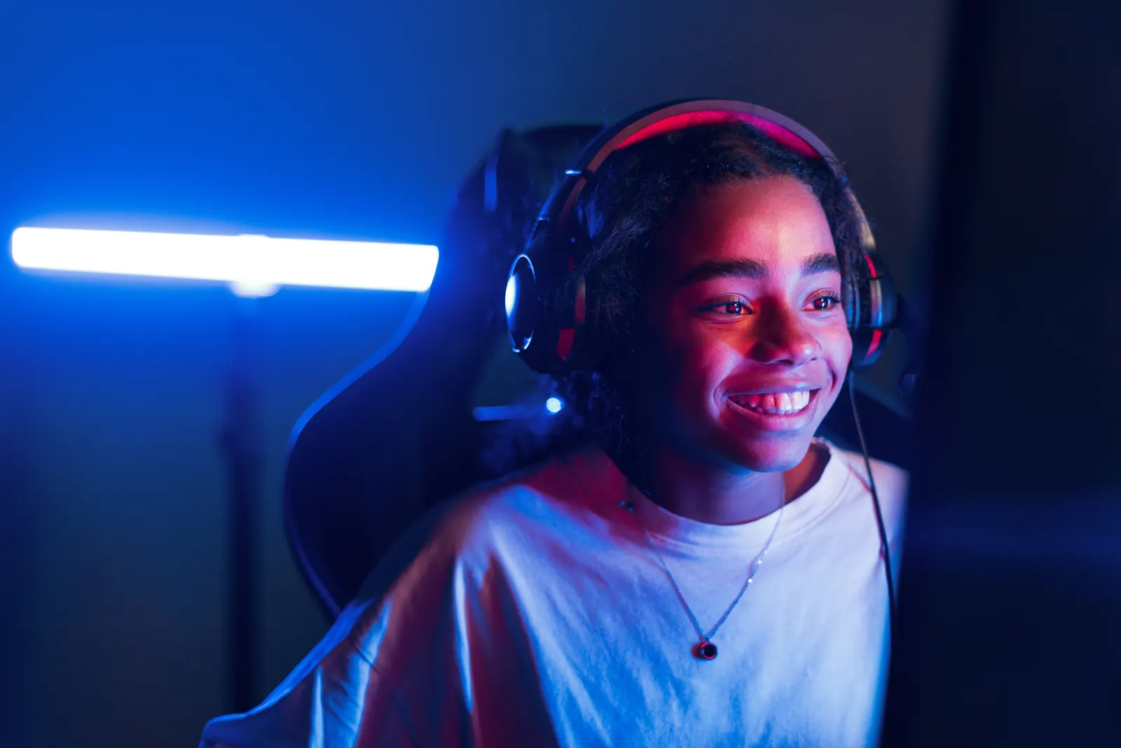 Lachende Gamerin mit Headset in blau-rotem Licht